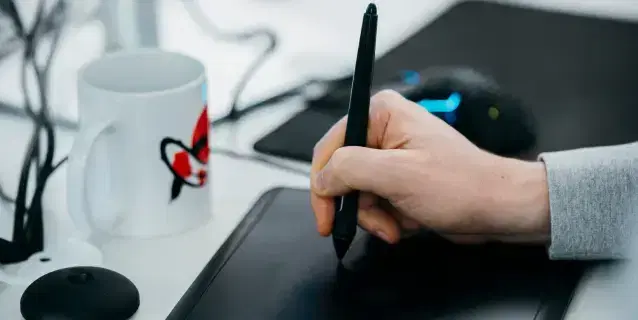 Крупный план руки, работающей с графическим планшетом, и кружка с логотипом Mighty Koi